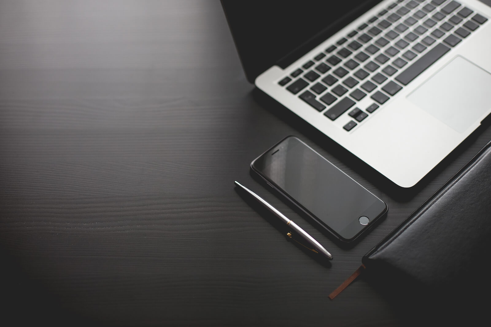 Dark desk with modern laptop and phone